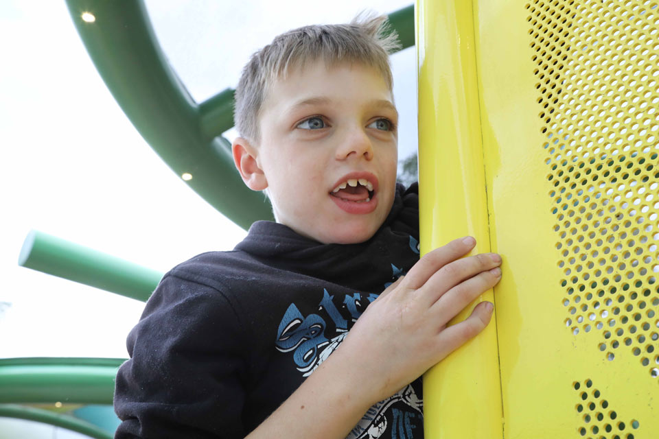 Boy standing next to a colored position with small holes in it.

