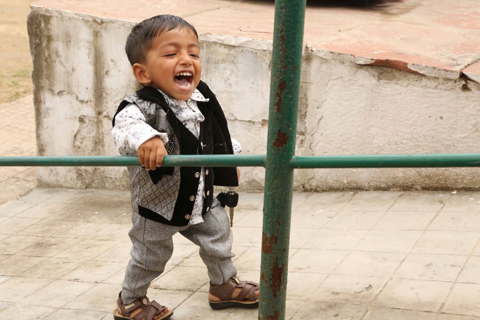 A very happy little boy walks up a ramp.